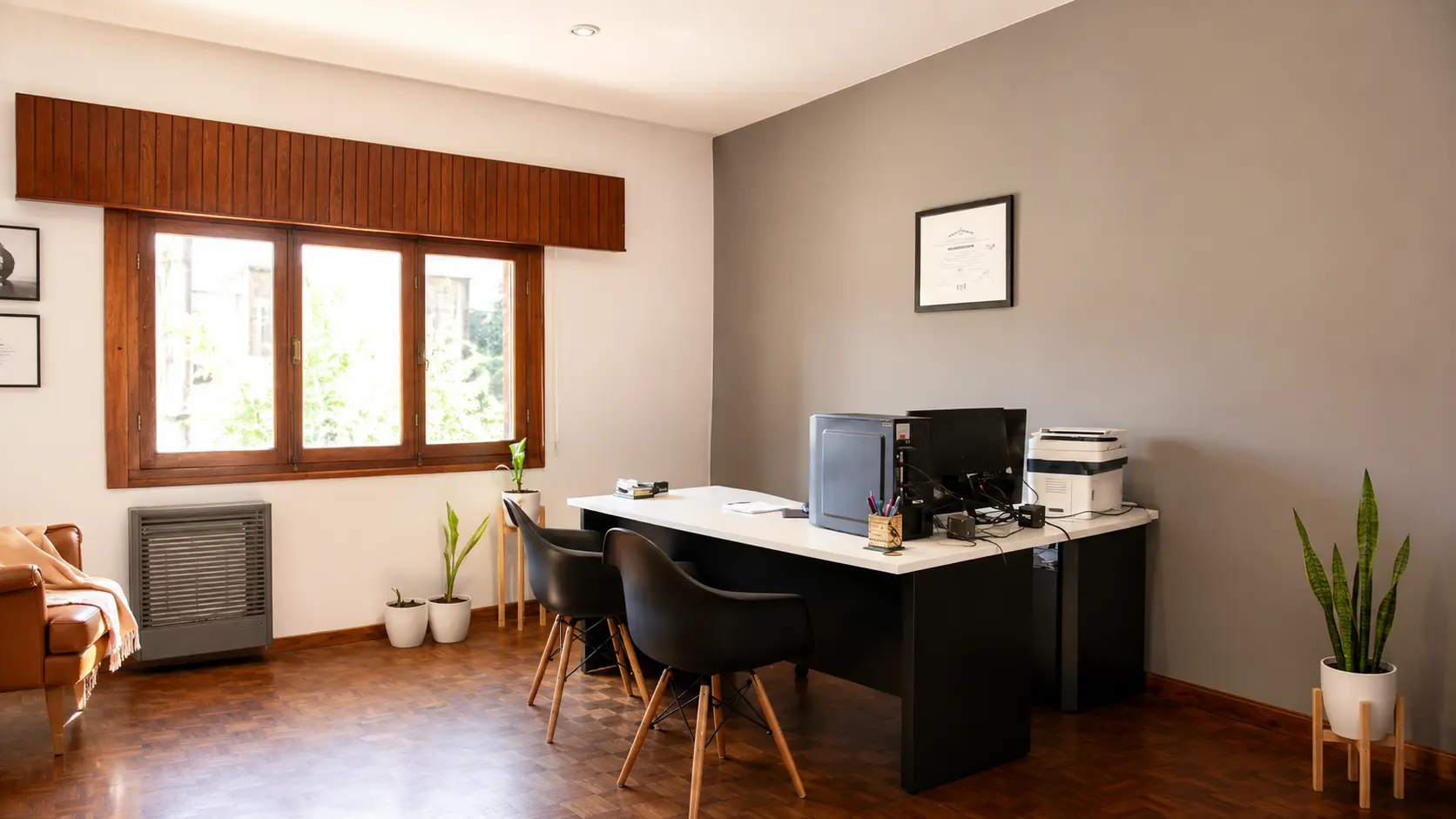 Interior del estudio MD Abogados Asociados en Junín — escritorio con sillas Eames, ventana grande y diploma enmarcado